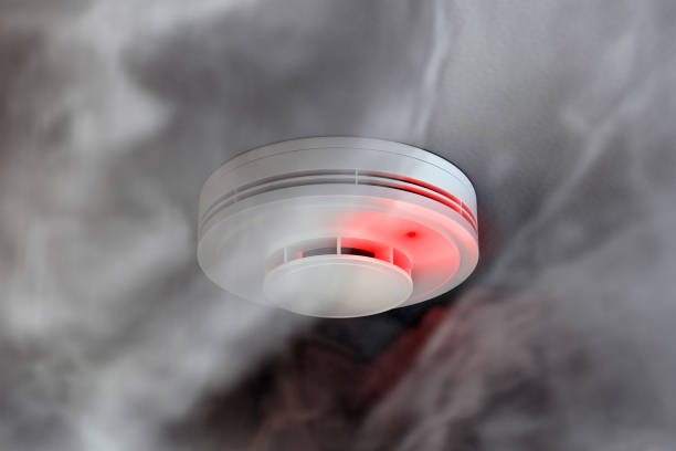 dire детектор дыма сигнализации с красным светодиодным индикатором на потолке - watch battery стоковые фото и изображения