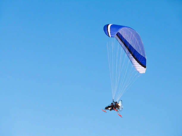 istock Man flying on paraglider, glider with motor. Vehicle in clear blue sky. 1163925807