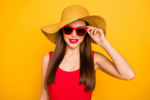 Close up photo of cheerful amazing lady bright lipstick nice colorful look trip voyage, wear specs sun hat red swimming suit isolated yellow background