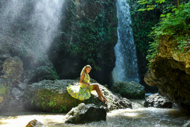 Young woman relaxes in pool below waterfall, Soca River