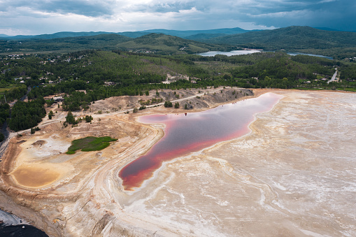 Pink colored water reservoir; copper digging production site; contamination territory; ecological catastrophe; drone flying over a water surface; aerial industrial landscape; anthropogenic influense