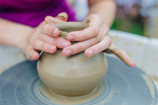 istock Women working on the potter's wheel. Hands sculpts a cup from clay pot. 1163932220