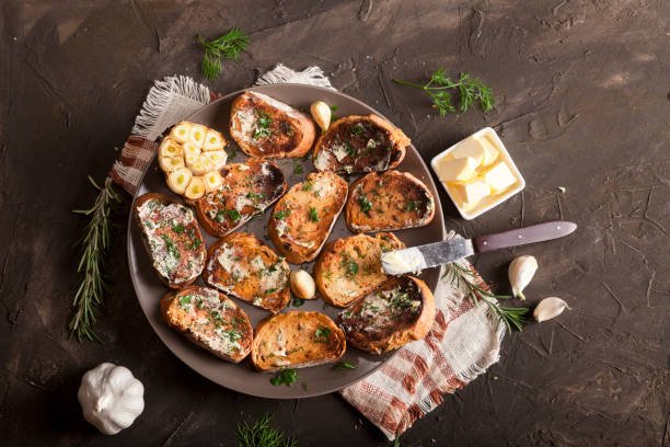 Sliced traditional toast bread with butter, garlic and herbs on a brown plate