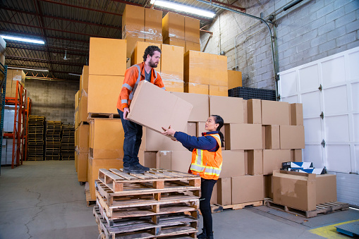 Un tema de seguridad en el lugar de trabajo de almacén industrial.  Un empleado de pie inseguramente en una pila de palets para llegar a las cajas más altas colocadas. photo