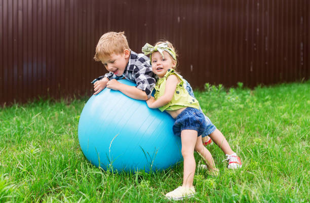 Children jumping on blue inflatable ball on the lawn.