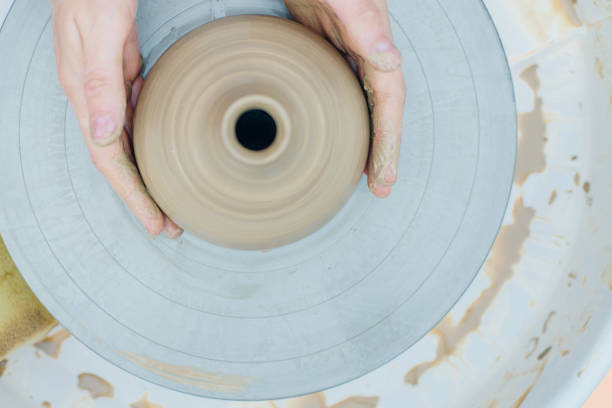 istock Women working on the potter's wheel. Hands sculpts a cup from clay pot. 1163933050