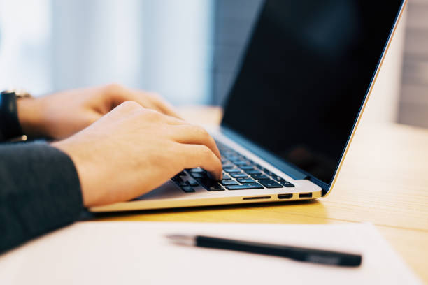 istock Sideview of man doing paperwork with laptop 1163934344