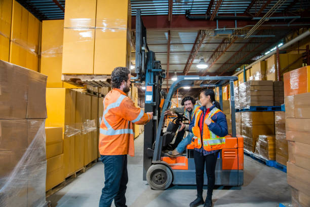 istock An industrial warehouse workplace safety topic. A worker in the danger zone, working too close to a raised forklift carrying a load. 1163934451