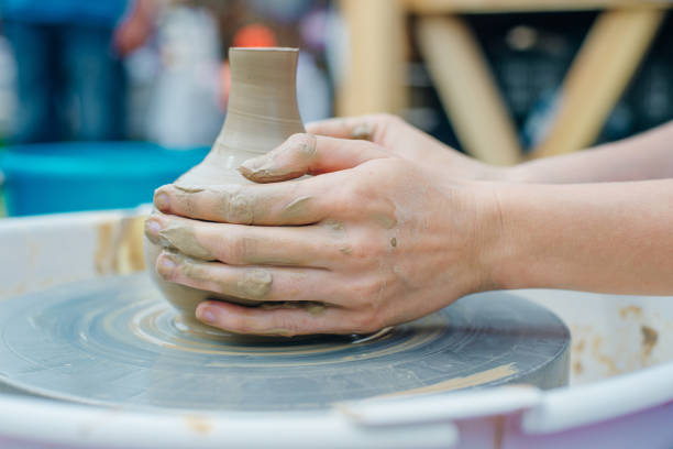 Women working on the potter's wheel. Hands sculpts a cup from clay pot. Workshop on modeling on the potter's wheel.