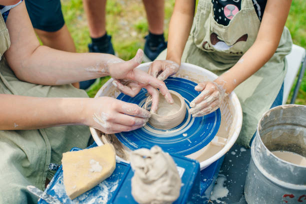 istock Women working on the potter's wheel. Hands sculpts a cup from clay pot. 1163934820