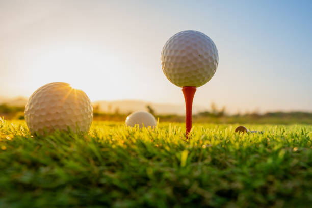 esporte ao ar livre, bola de golfe em tee pegs pronto para jogar na grama verde e luz brilha por do sol - golf lifestyles sport golf swing - fotografias e filmes do acervo