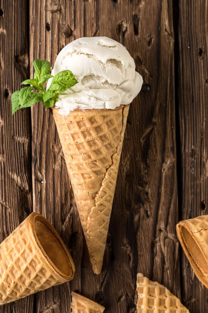 istock Top view white ice cream in waffle cone on rustic background 1163946437