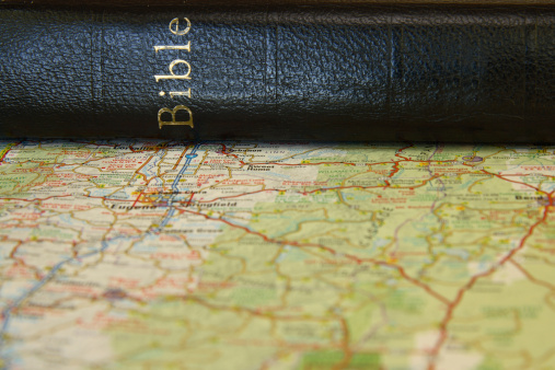 Black Bible with gold letters on a roadmap.