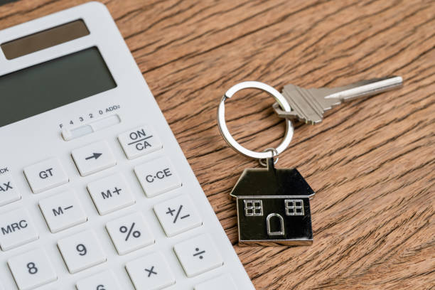 istock Home key with house keyring or keychain with white calculator on wooden table using as mortgage calculation or buy and sell property and real estate 1163954919