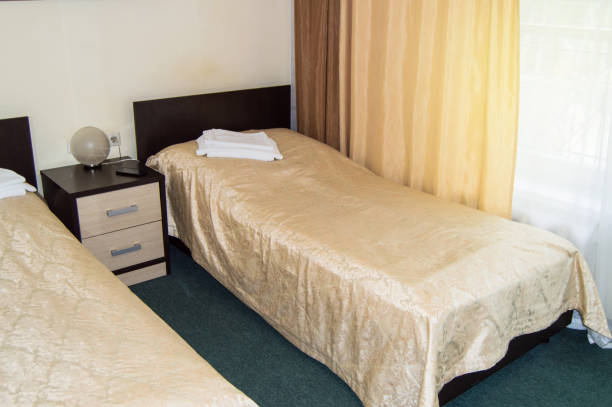 シングルベッド2台、ベッドサイドテーブル、タオル、テーブルランプ付きのモダンなダブルルーム、旅行者のための居心地の良い安価な部屋、良いサービスとホテル経営者のおもてなし - double bed headboard hotel room design ストックフォトと画像