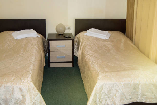 シングルベッド2台、ベッドサイドテーブル、タオル、テーブルランプ付きのモダンなダブルルーム、旅行者のための居心地の良い安価な部屋、良いサービスとホテル経営者のおもてなし - double bed headboard hotel room design ストックフォトと画像