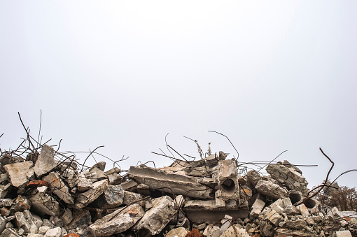 La armadura que se pega de montones de escombros de ladrillo, piedra y escombros de hormigón contra el cielo en una neblina. photo
