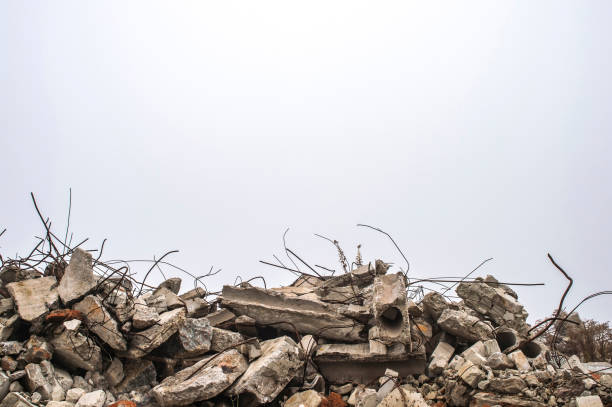 The rebar sticking up from piles of brick rubble, stone and concrete rubble against the sky in a haze. The rebar sticking up from piles of brick rubble, stone and concrete rubble against the sky in a haze. Remains of the destroyed building. Copy space. war stock pictures, royalty-free photos & images