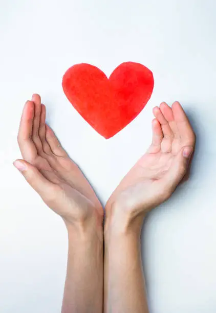 Photo of Heart sign drawn with a marker pen and hands embracing it.