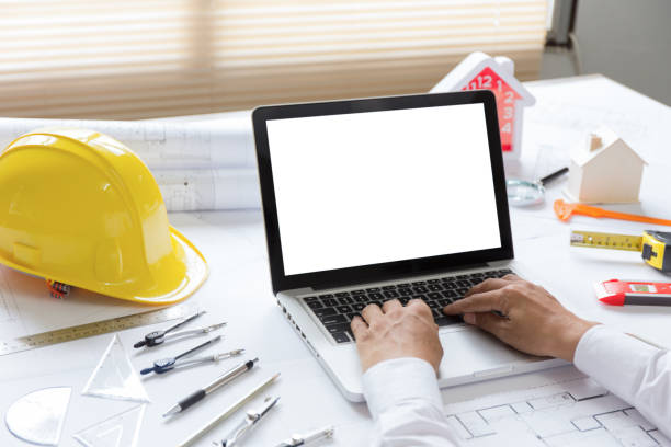 istock architect hands using laptop with a building of blueprint and engineering tools on working table. 1163957995