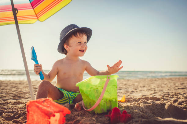 Little boy sitting on the beach and building a sandcastle Cute happy child on beach vocations near the sea pinus pinea photos stock pictures, royalty-free photos & images