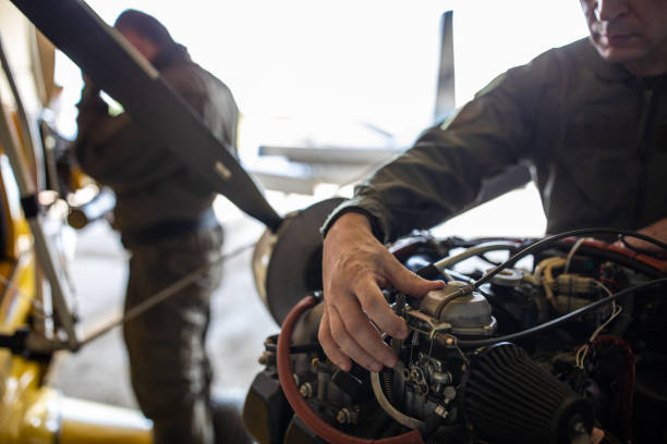 Two mature man in uniforms analyzing the airplane engine in the hangar together