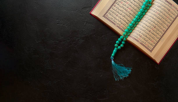 Koran with rosary beads and muslim hat on black stone or slate texture background Islamic concept for Ramadhan. Flat lay composition of Holy Book for muslim Quran koran photos stock pictures, royalty-free photos & images