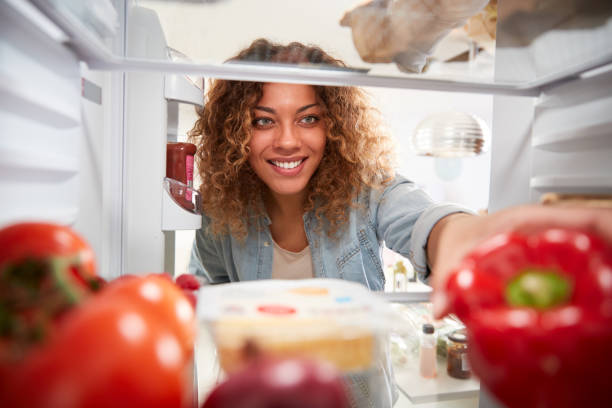 View Looking Out From Inside Of Refrigerator As Woman Opens Door And Unpacks Shopping Bag Of Food View Looking Out From Inside Of Refrigerator As Woman Opens Door And Unpacks Shopping Bag Of Food refrigerator photos stock pictures, royalty-free photos & images
