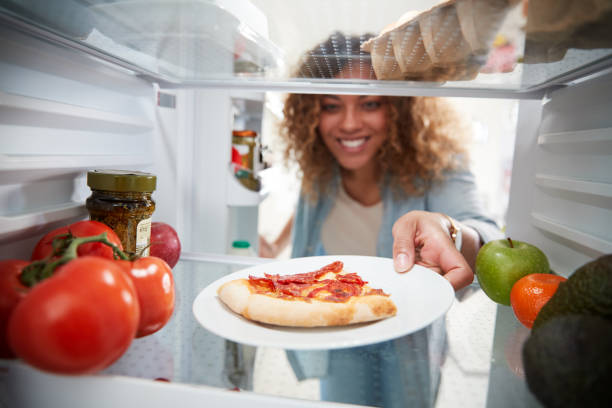 View Looking Out From Inside Of Refrigerator As Woman Opens Door For Leftover Takeaway Pizza Slice View Looking Out From Inside Of Refrigerator As Woman Opens Door For Leftover Takeaway Pizza Slice leftovers photos stock pictures, royalty-free photos & images