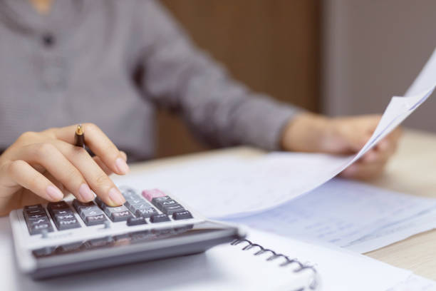 istock Close up young woman hand is writing in a notebook and using calculator counting making notes Accounting at doing finance at home office. Savings finances concept. note pad 1163966931