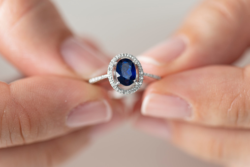 Hands holding diamond ring. Sapphire.