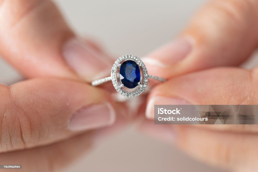 Woman Holding a Blue Diamond Ring Hands holding diamond ring. Sapphire. Sapphire Stock Photo
