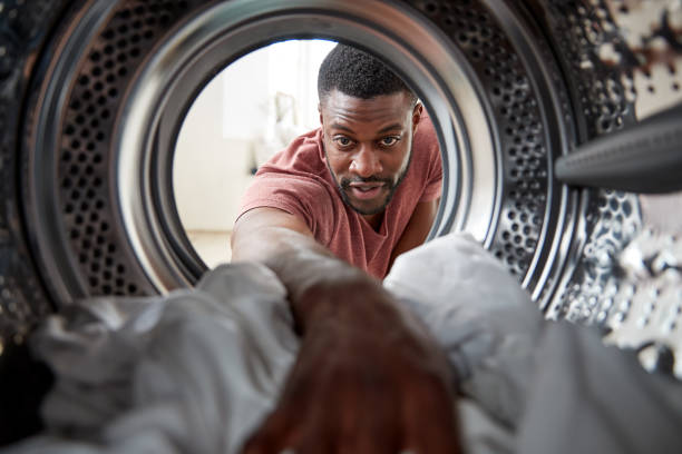 blick aus der innen-waschmaschine als mann tut weiße wäsche - haushaltsaufgabe fotos stock-fotos und bilder