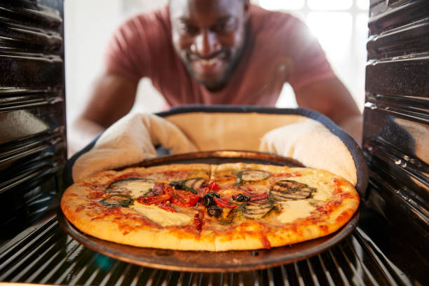View Looking Out From Inside Oven As Man Cooks Fresh Pizza