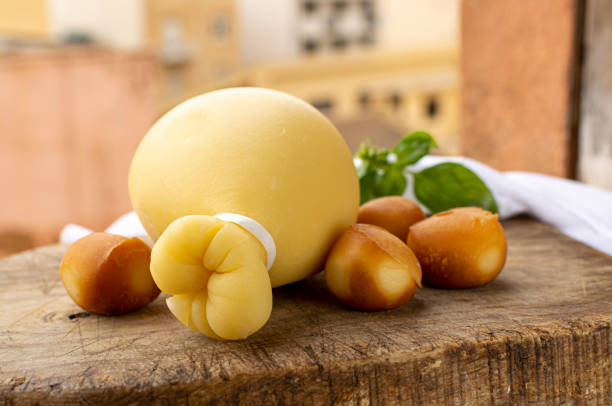 provolone italiano caciocavallo formaggi stagionati e affumicati in forma di lacrima con houises gialle del centro storico italiano sullo sfondo - trapani close up sicily italy foto e immagini stock