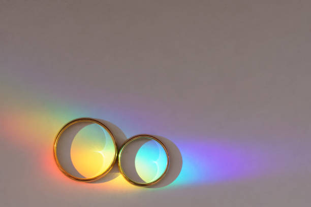 Background with two wedding rings with rainbow. Background with two wedding rings with rainbow light. marriage equality stock pictures, royalty-free photos & images