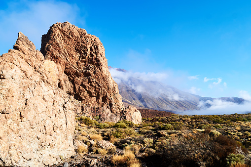 big rocks and yellow stones in the desert landscape with mountains and clouds on the background