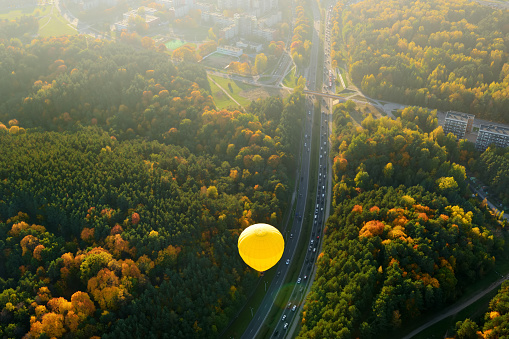 Aerial view of yellow hot air balloon flying over Vilnius city on sunny autumn evening. Vilnius is one of the few European capital cities, where hot air balloons are allowed to fly.