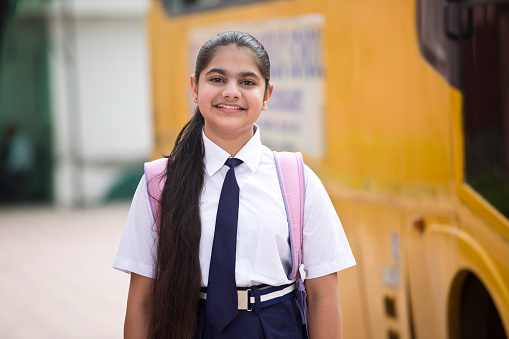 Portrait of schoolgirl in uniform with bag and water bottle