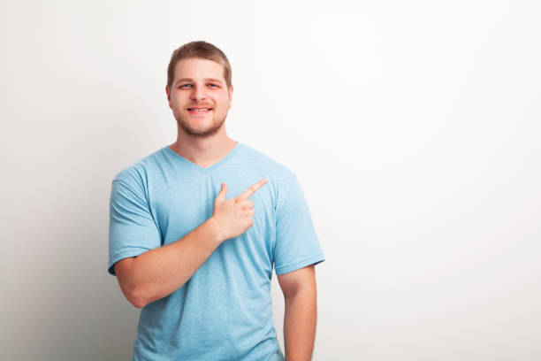 istock Portrait of handsome smiling young man pointing to empty copy space 1163982168