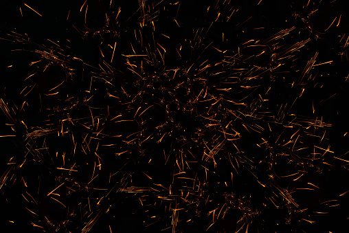 Sparks on a black background from welding steel. Sparks fly in different directions on a black background.