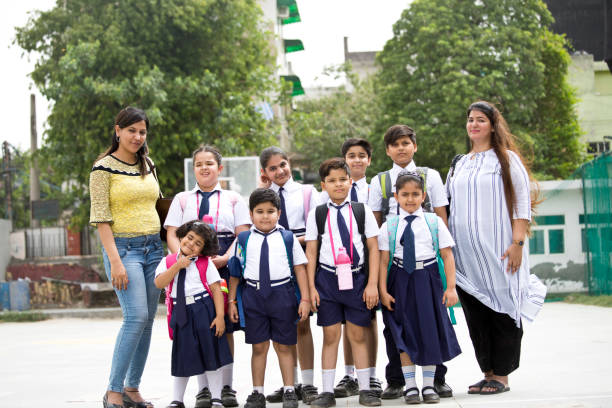 istock Group of school children with teachers standing in group 1163982594