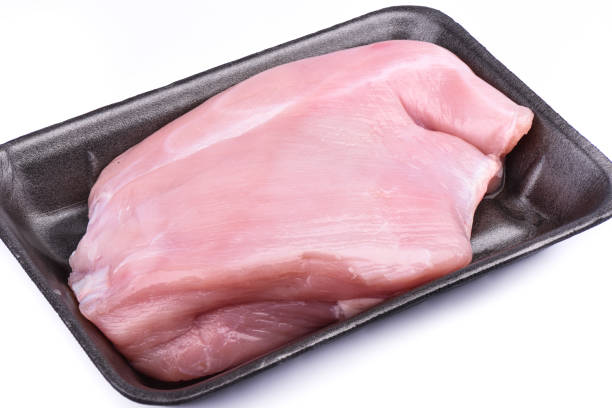 istock Raw turkey fillet in a plastic tray over white background. 1163989945
