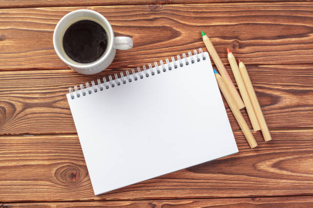 Office desk table top view. Notepad with blank pages on wooden table