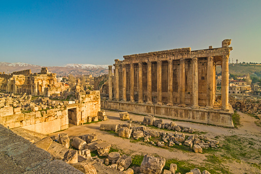 Lebanon - Baalbek (Heliopolis) - Massive ruins of the Temple of Bacchus and the part of the Temple of Jupiter in an impressive ancient archeological temple complex with snow capped peaks in a distance. UNESCO World Heritage site from 1984