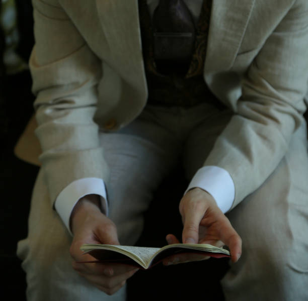 istock young man in suit sitting on sofa and reading a book 1163991004