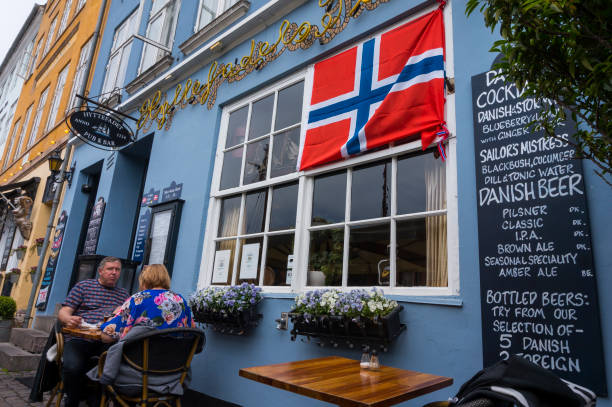 コペンハーゲンの有名なnyhavn桟橋でヴィンテージの昔ながらのレストランで屋外レストランで食事を楽しむ友人 - denmark house flag danish flag ストックフォトと画像
