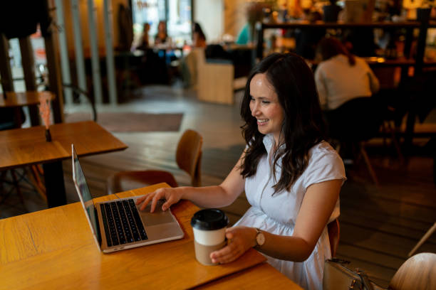 istock Cheerful woman uses laptop in restaurant 1163992225