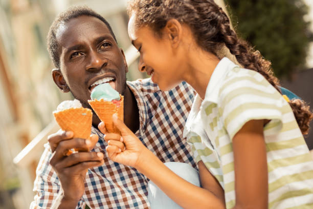istock Charming little female feeding her daddy with ice-cream 1163999234