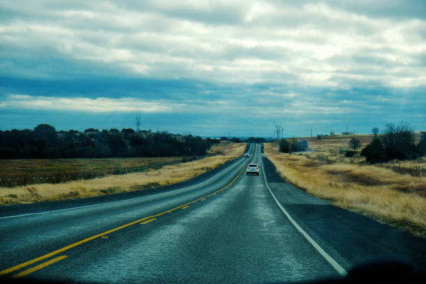 Travel concept with car driving through countryside on road during dreary day.